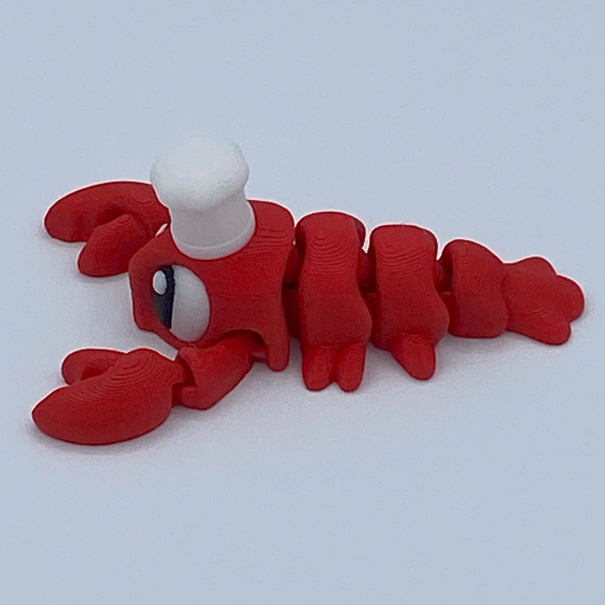 Red toy lobster chef with a white top on a light gray background