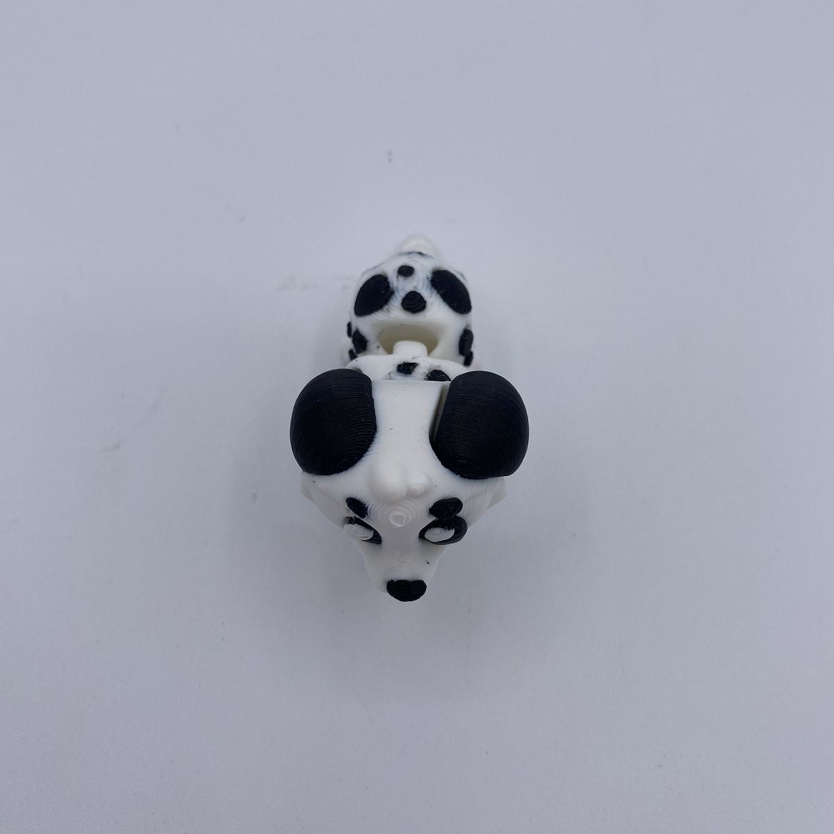 A small black and white dalmatian dog head charm or bead shown from above on a plain light background.