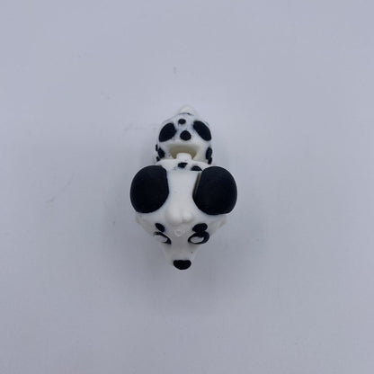 A small black and white dalmatian dog head charm or bead shown from above on a plain light background.