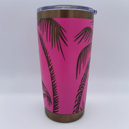 A stainless steel travel tumbler with a bright pink and a palm tree pattern, featuring a clear plastic lid on a copper background.