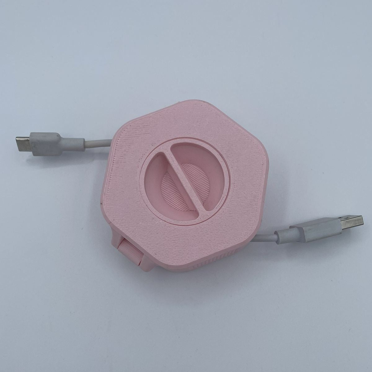 Pink retractable cable with USB connectors on a light gray background