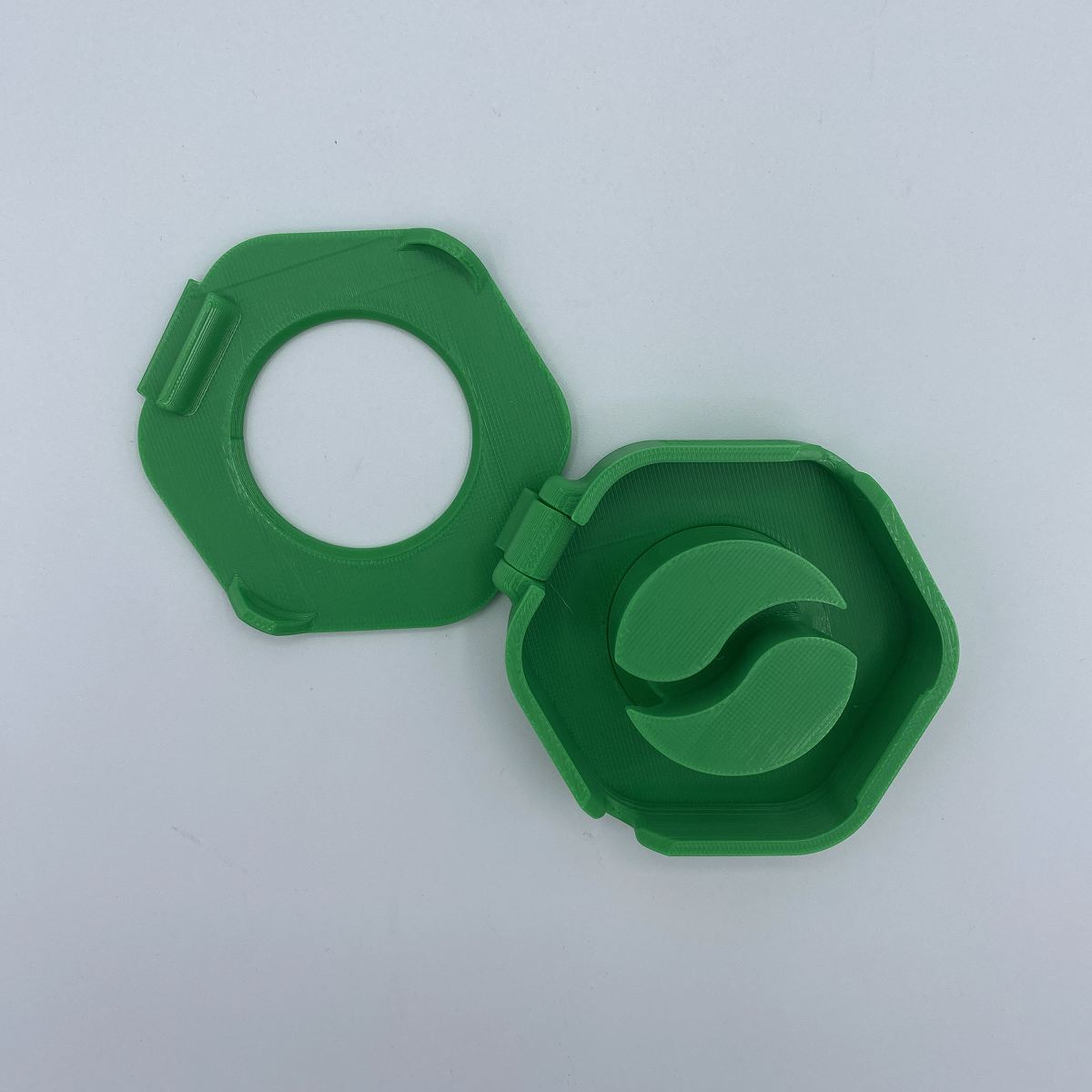 Green plastic cable organizer hexagonal on a light gray background